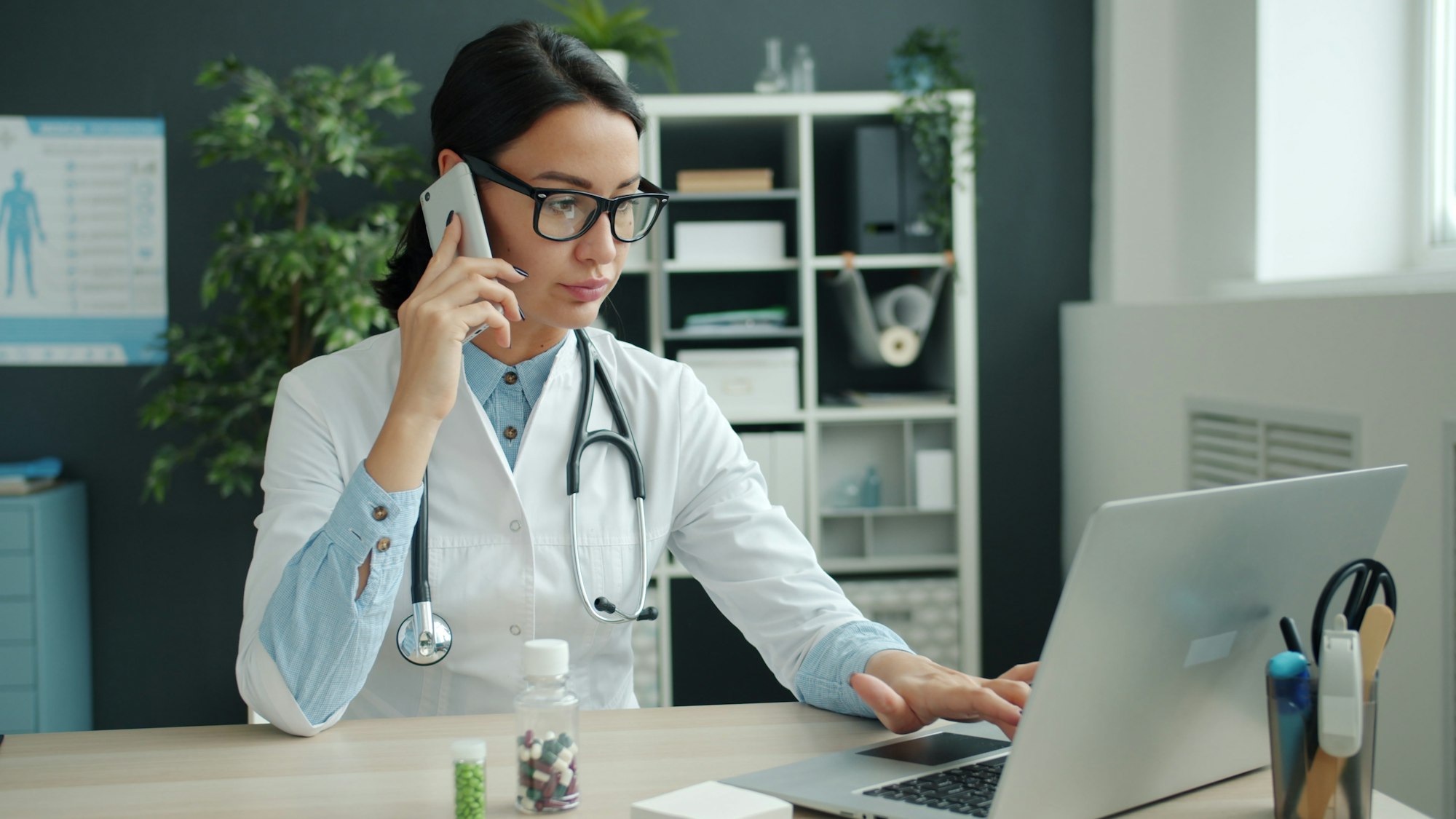 A doctor at her desk taking a call on her mobile phone