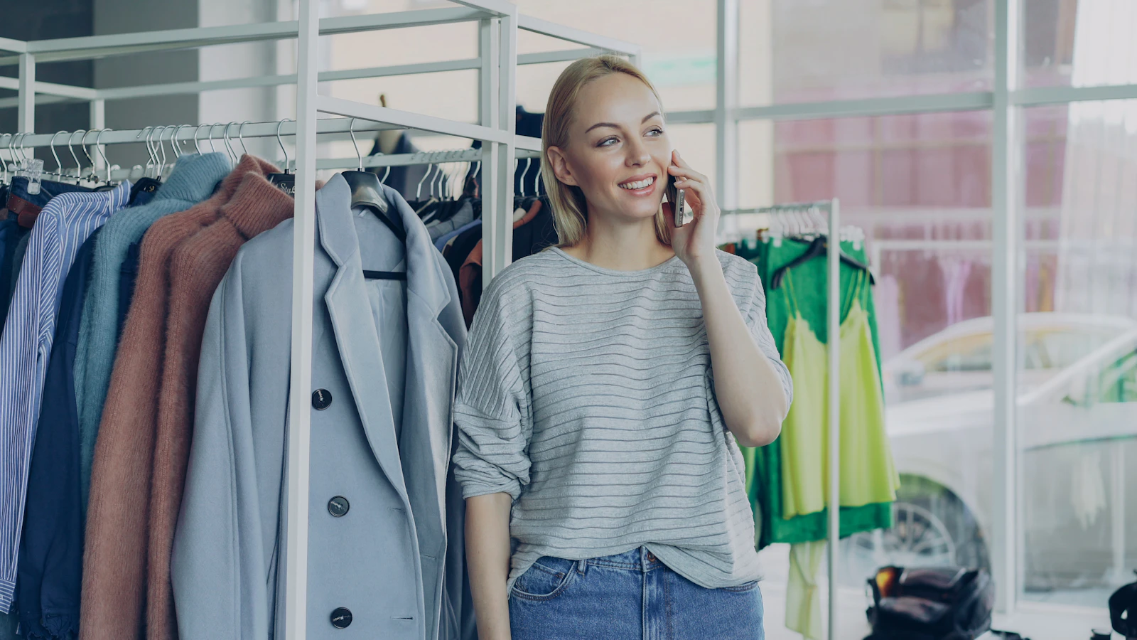 A store manager on a call on the shop floor, between racks of coats