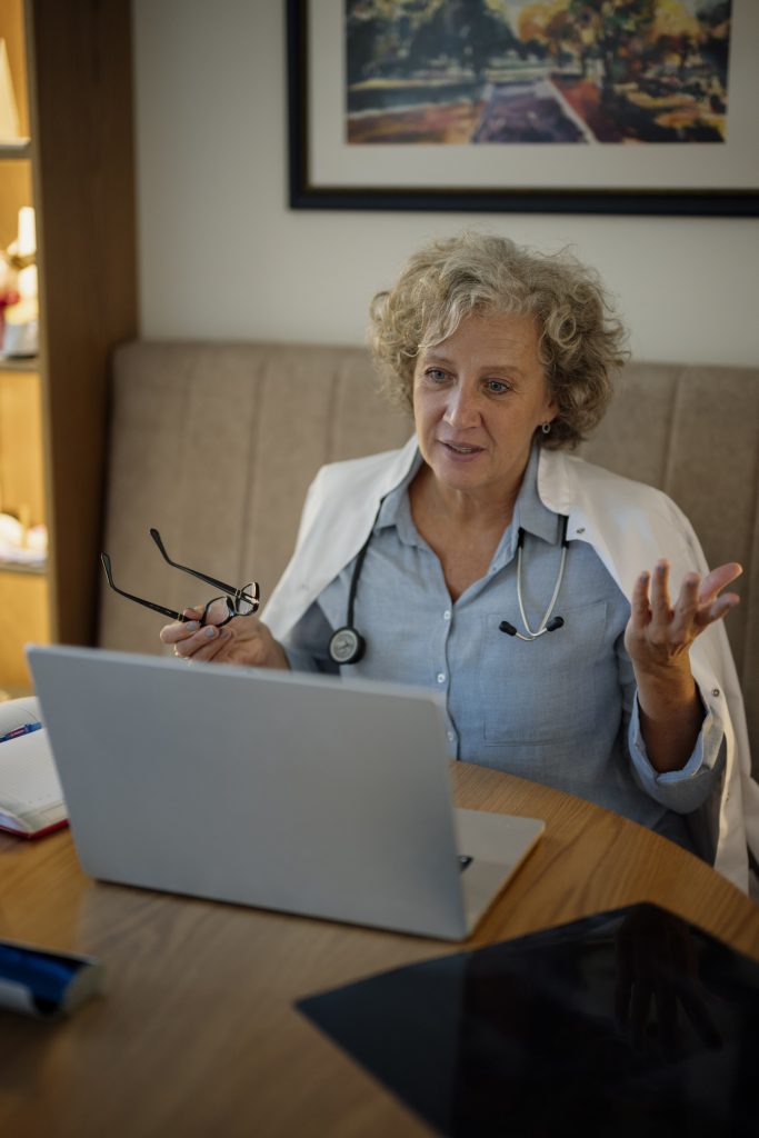 A doctor talking on a video call from her laptop