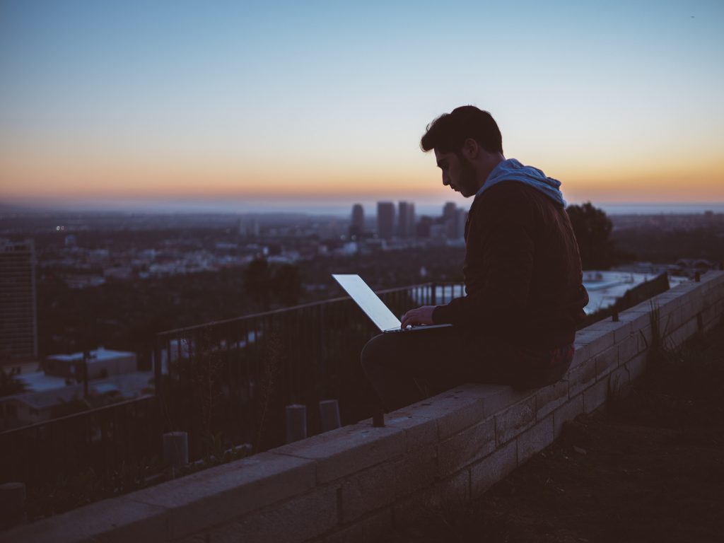 A man working on his laptop on a rooftop at dusk