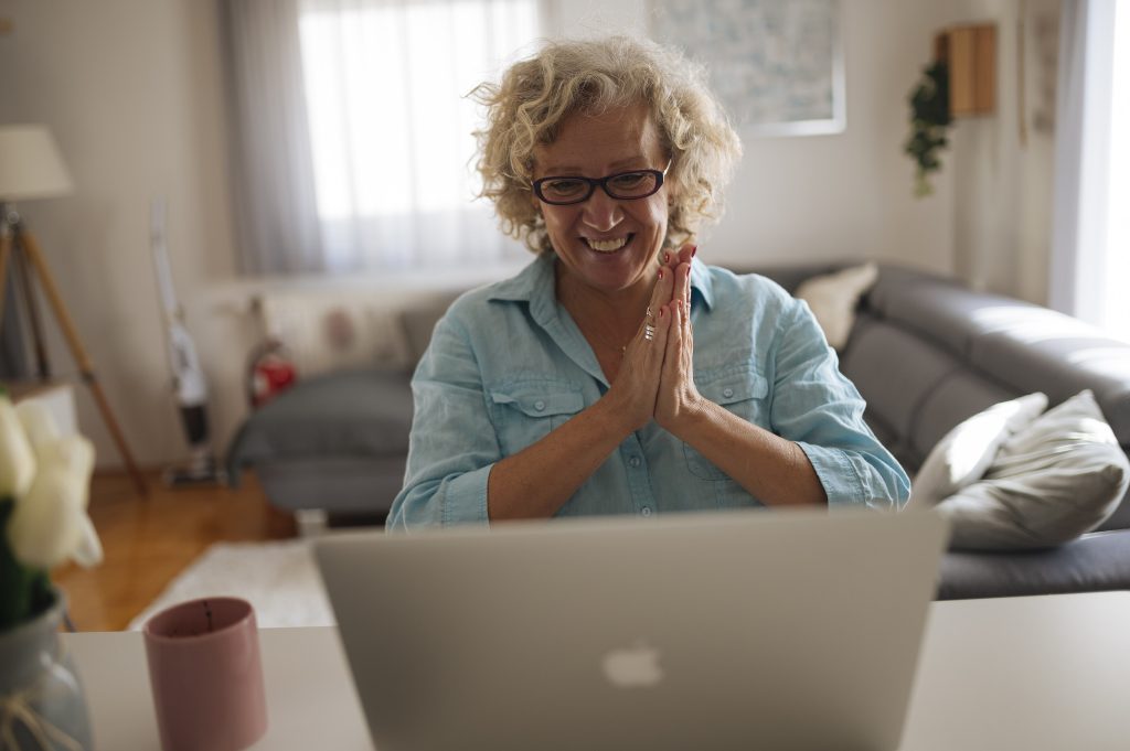 A woman greeting colleagues on a video call from her living room
