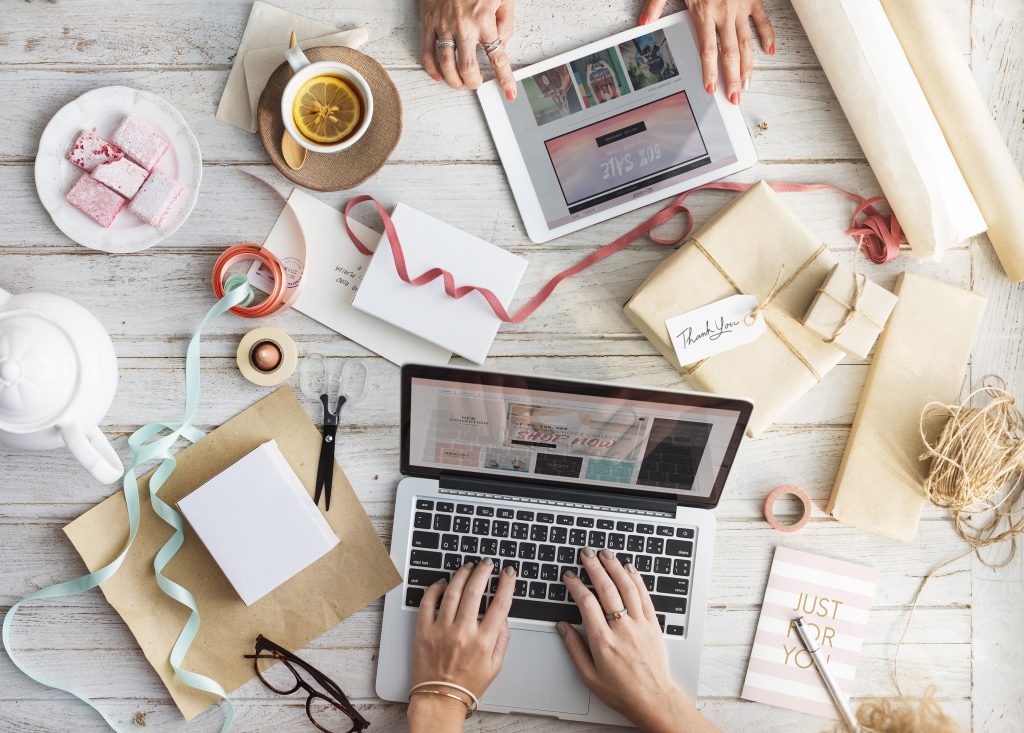 Hands typing on a laptop beside gift-wrapped orders