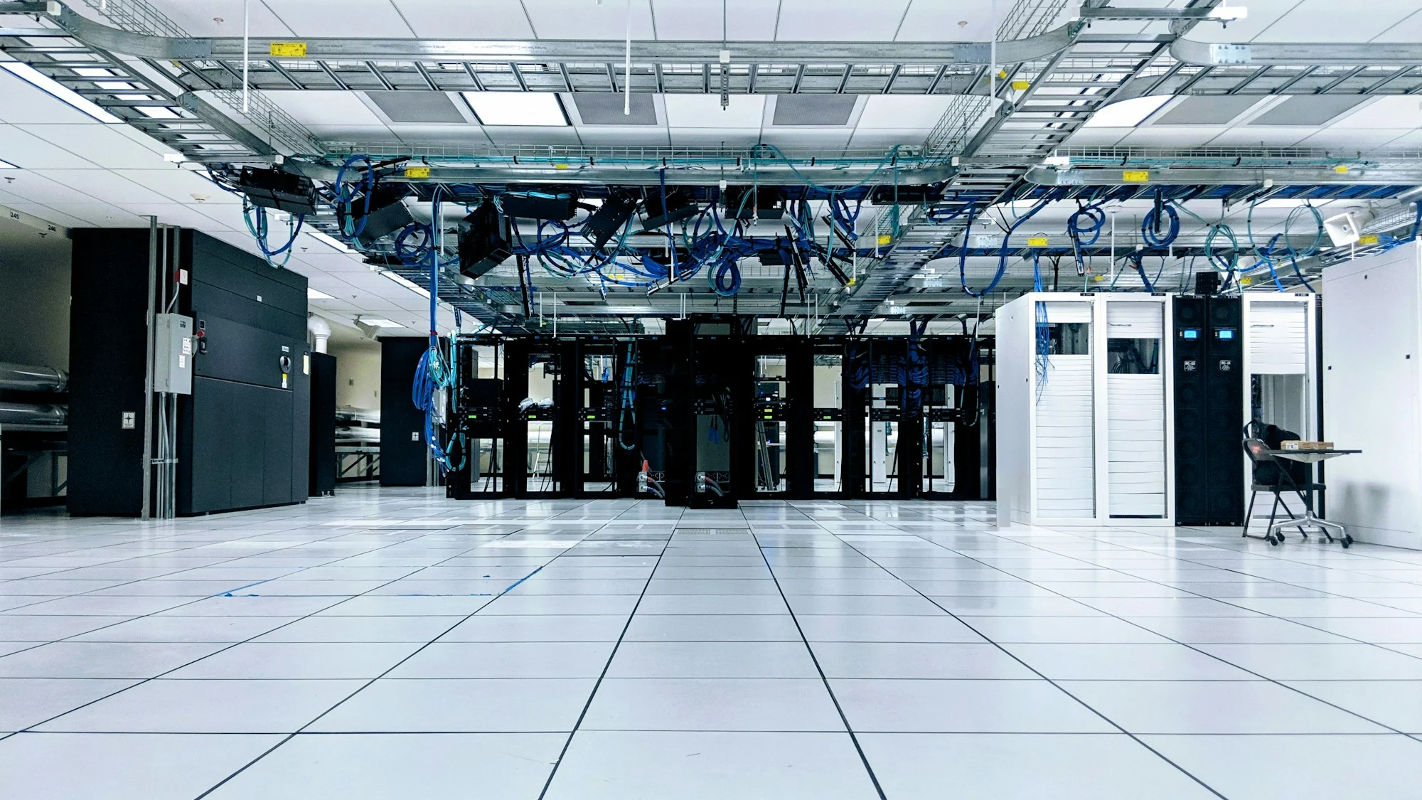 A data hall with rows of server racks under overhead cable trays