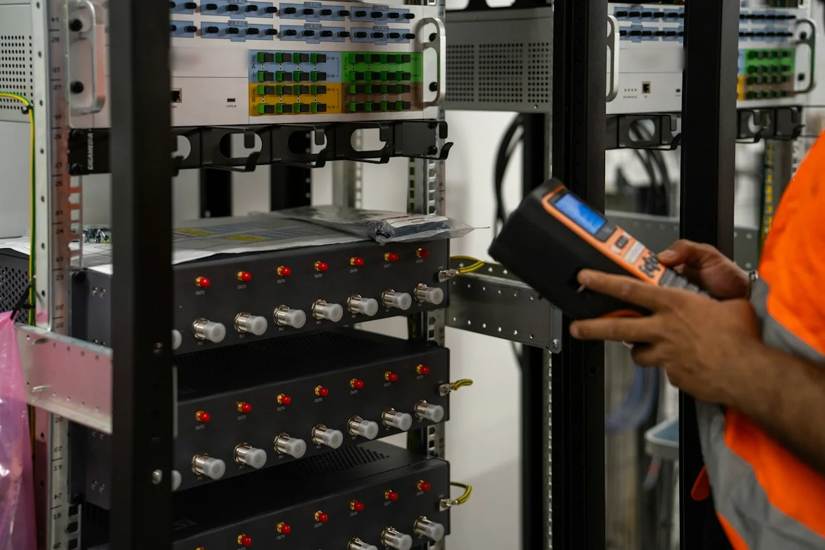 A technician testing a rack of equipment with a handheld meter