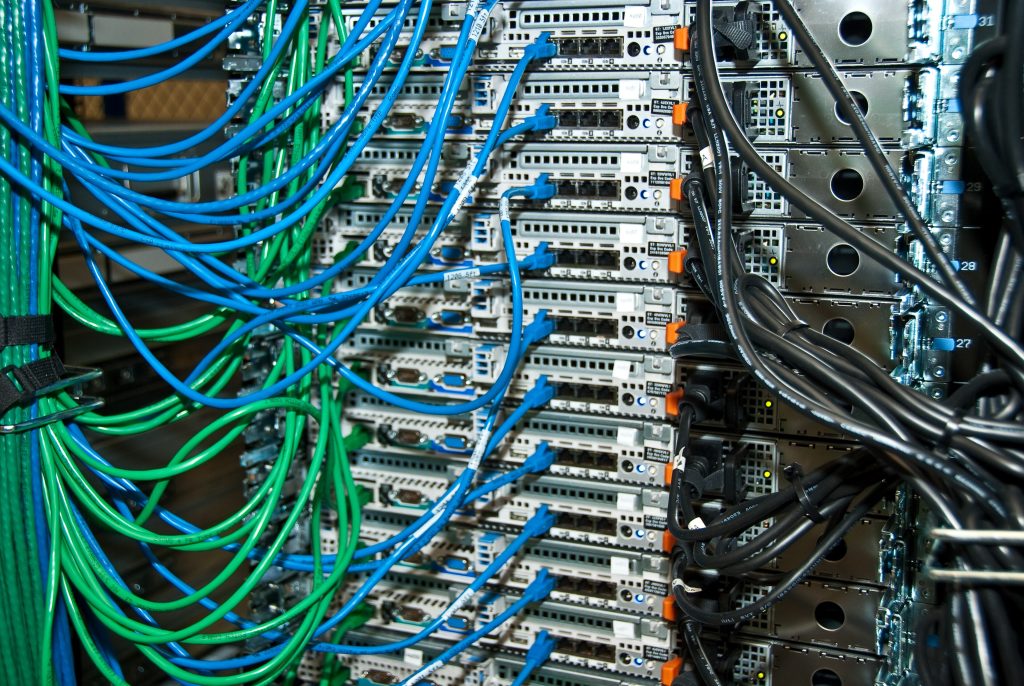 Blue and green network cables running into a rack of servers