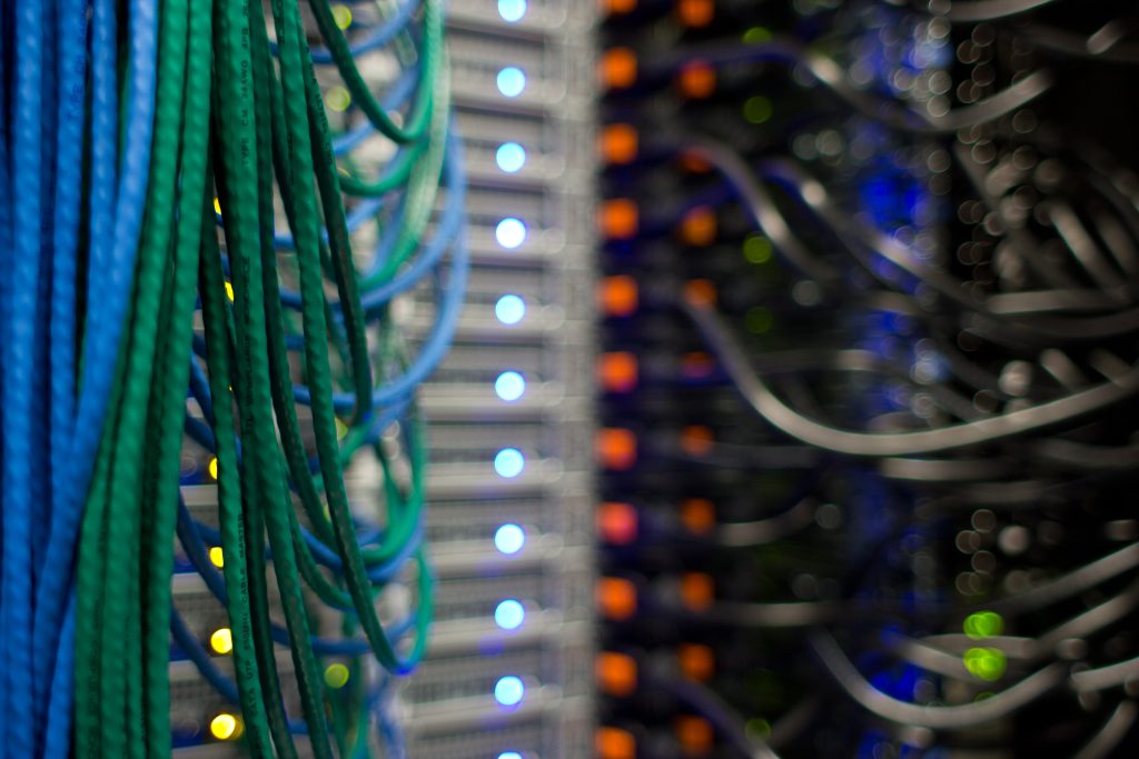Green and blue network cables and status lights at the back of a rack
