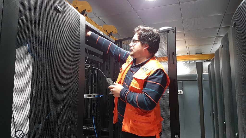 Technician in a safety vest working at an open rack