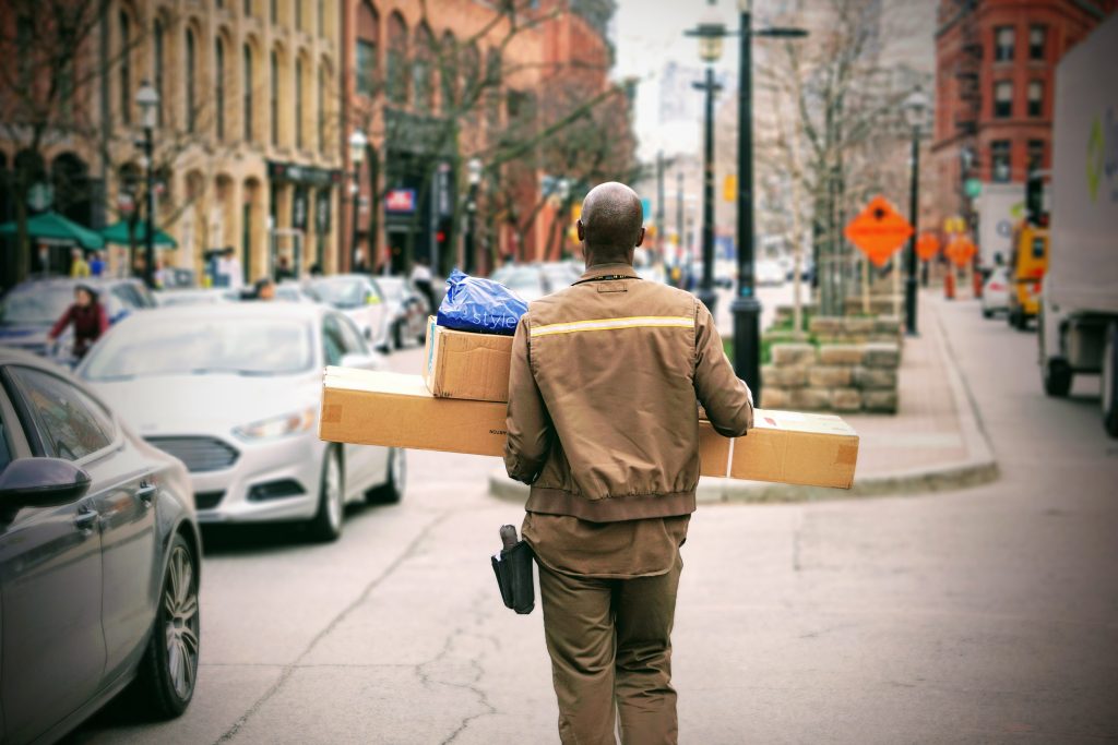 A courier carrying parcels along a city street