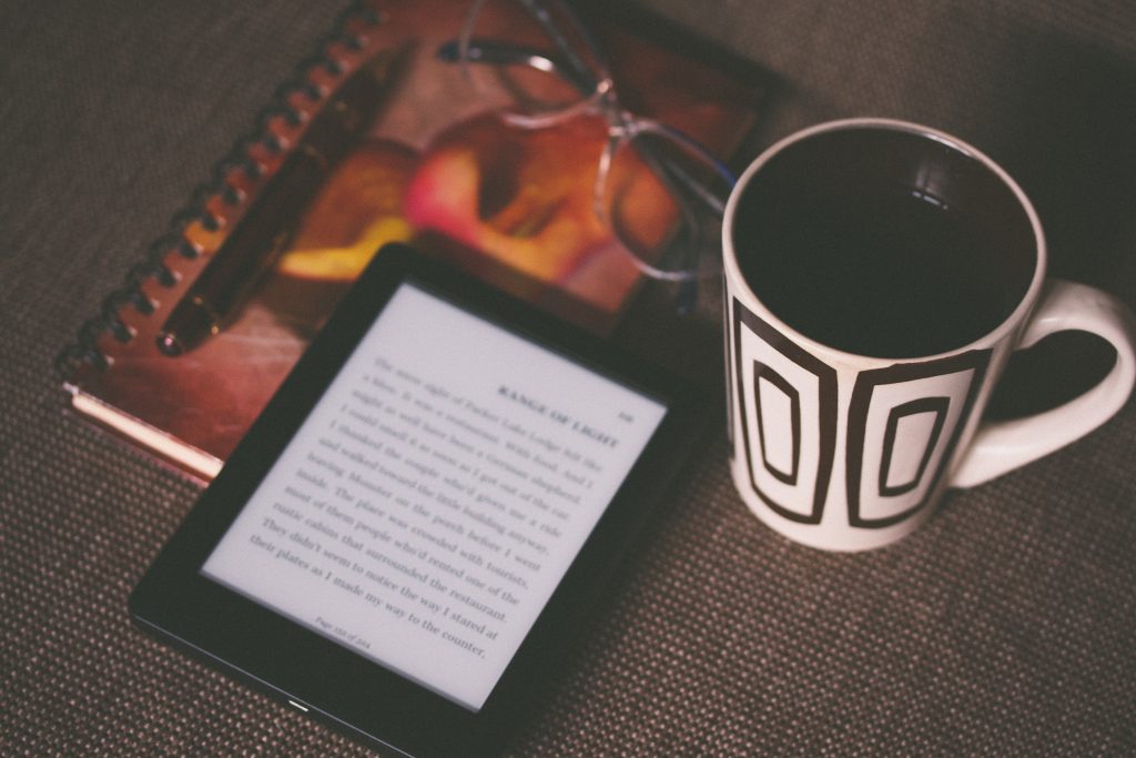 An e-reader and a mug of coffee on a table