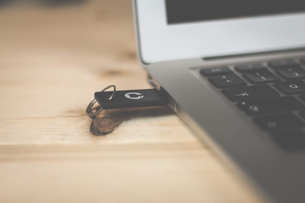 A USB stick plugged into a laptop on a wooden desk