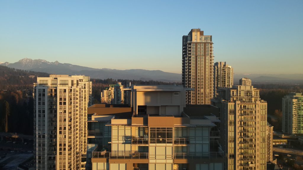 The towers of downtown Coquitlam, British Columbia, in evening light with mountains behind
