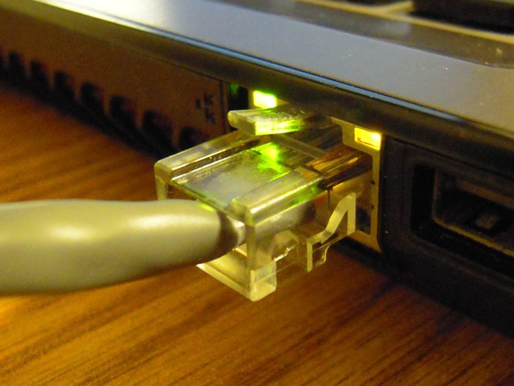 An ethernet cable plugged into a port, its green link light lit