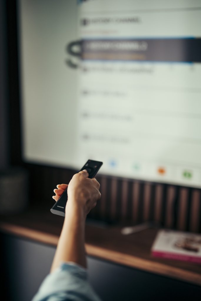 A person pointing a remote at a television at home