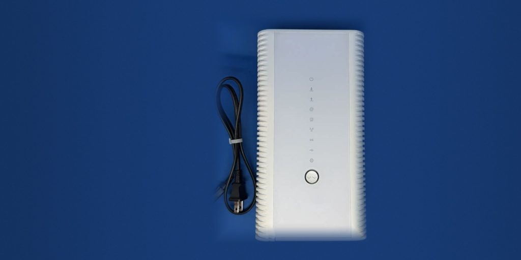 The white Hitron CODA-4582 modem standing beside its coiled power cord, on a blue ground