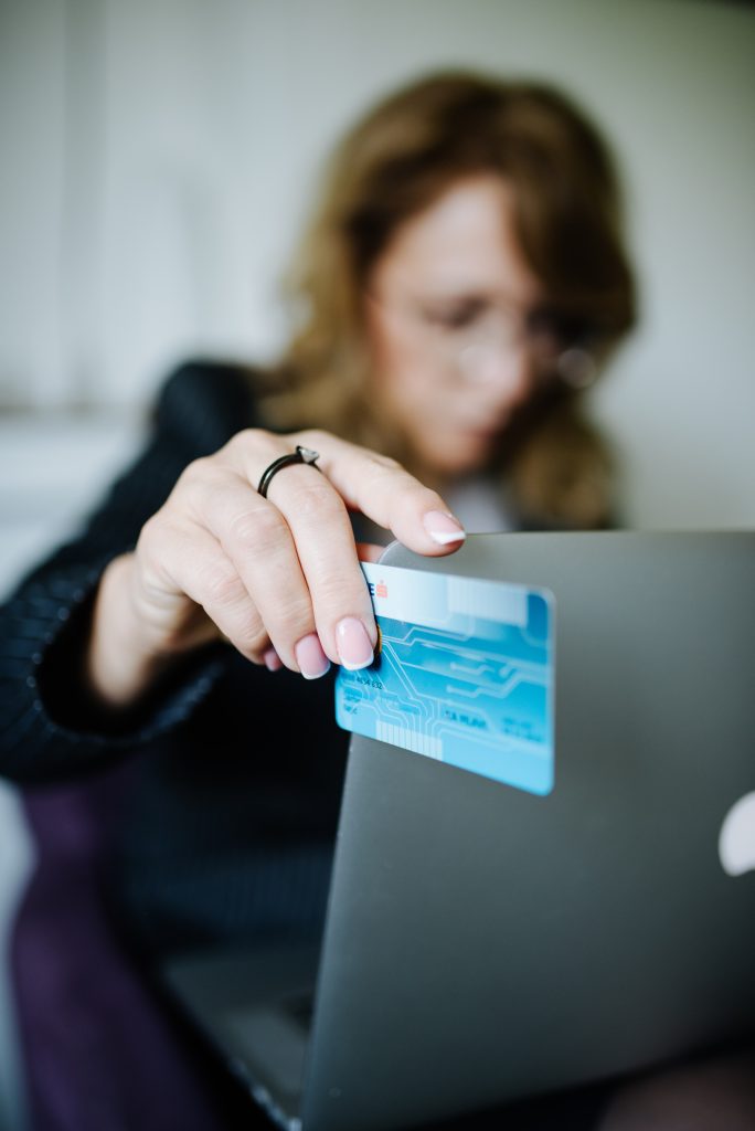 A person holding a bank card while shopping on a laptop at home
