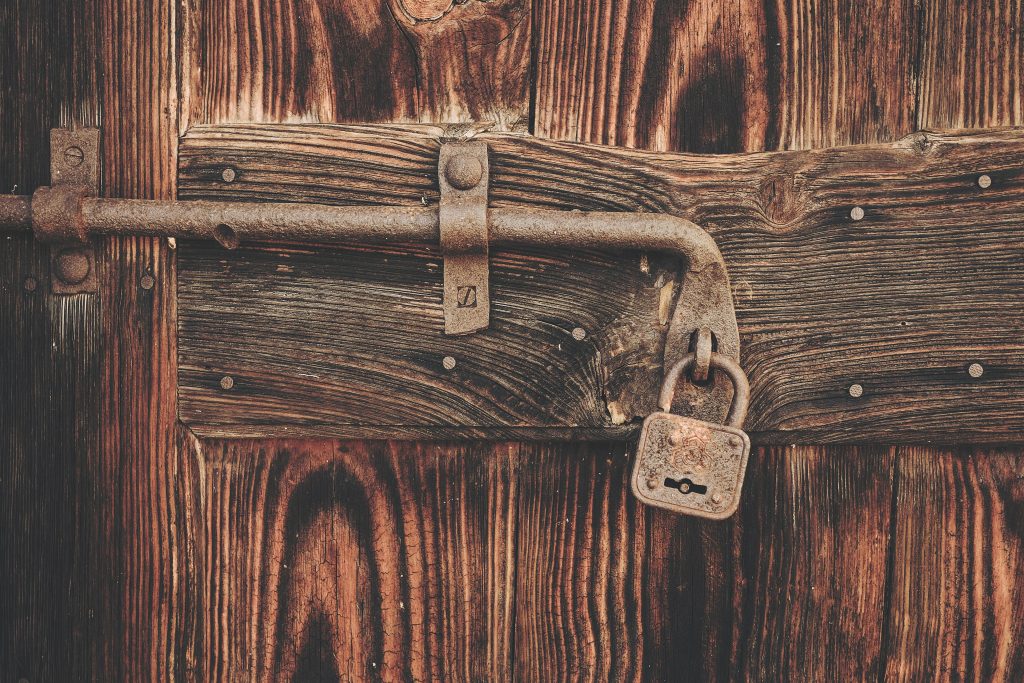 A small padlock on the hasp of a wooden chest
