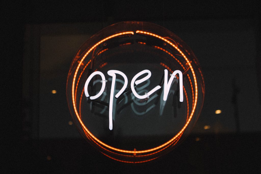 A round neon sign reading open