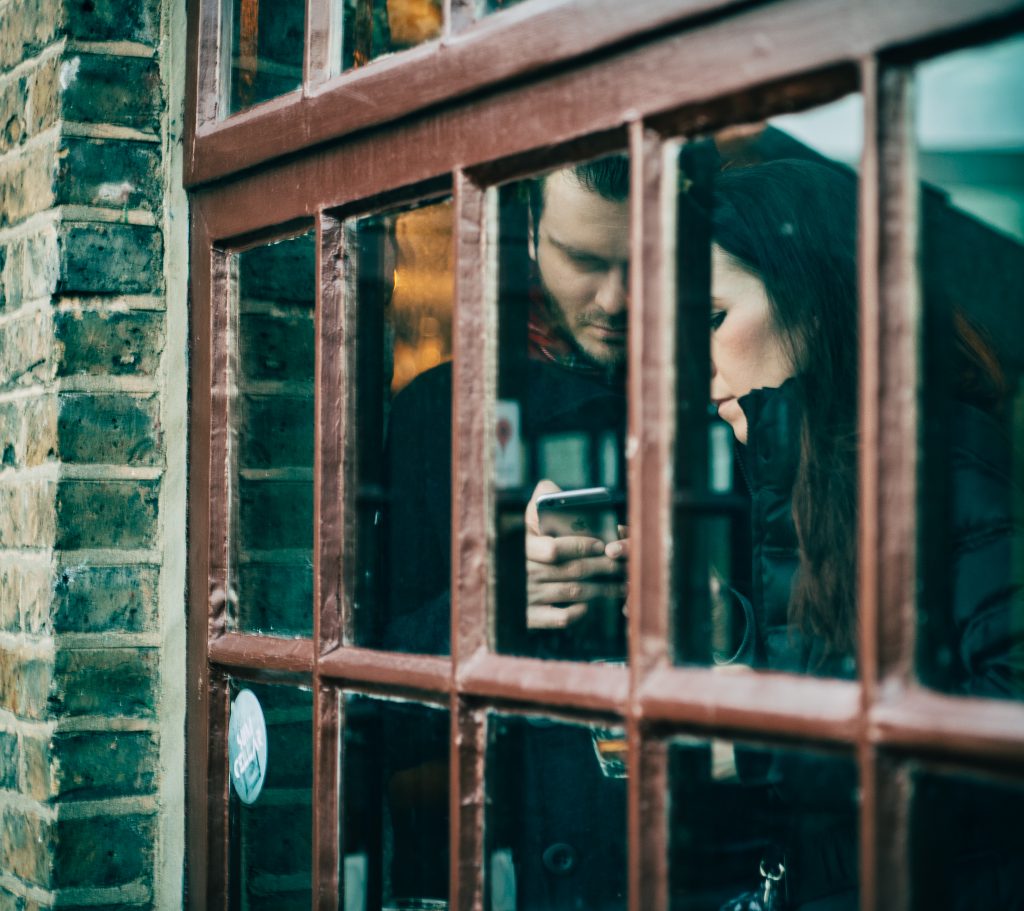 Two people looking at a phone through a window