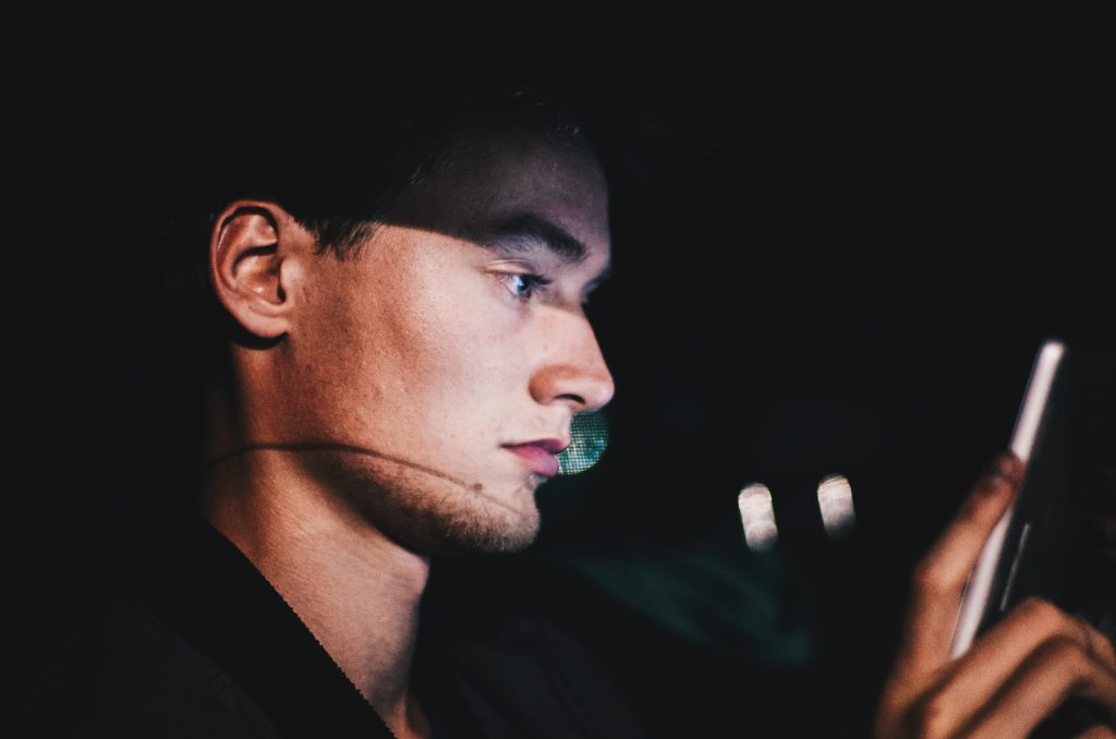 A man looking at his phone in a dark room