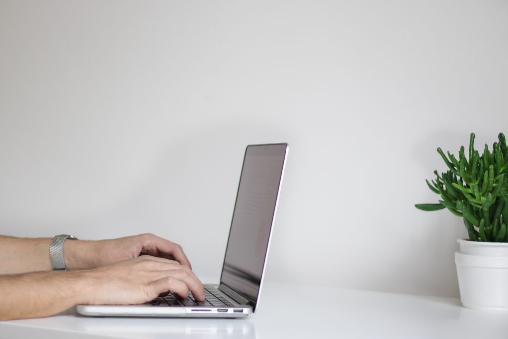 A tidy desk with an open laptop, a notebook and a cup of coffee
