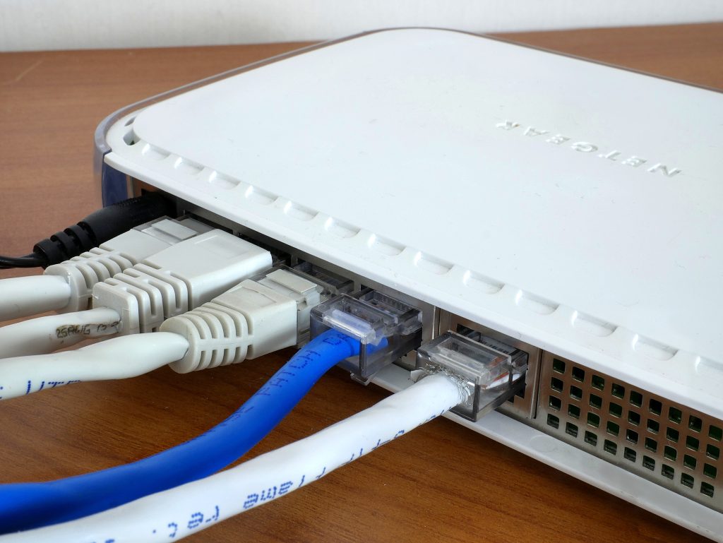 Blue and white network cables plugged into the back of a white router