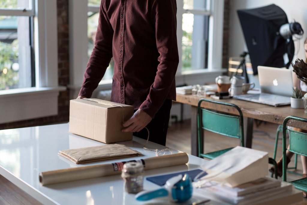 A person at a desk sealing a cardboard box for shipping