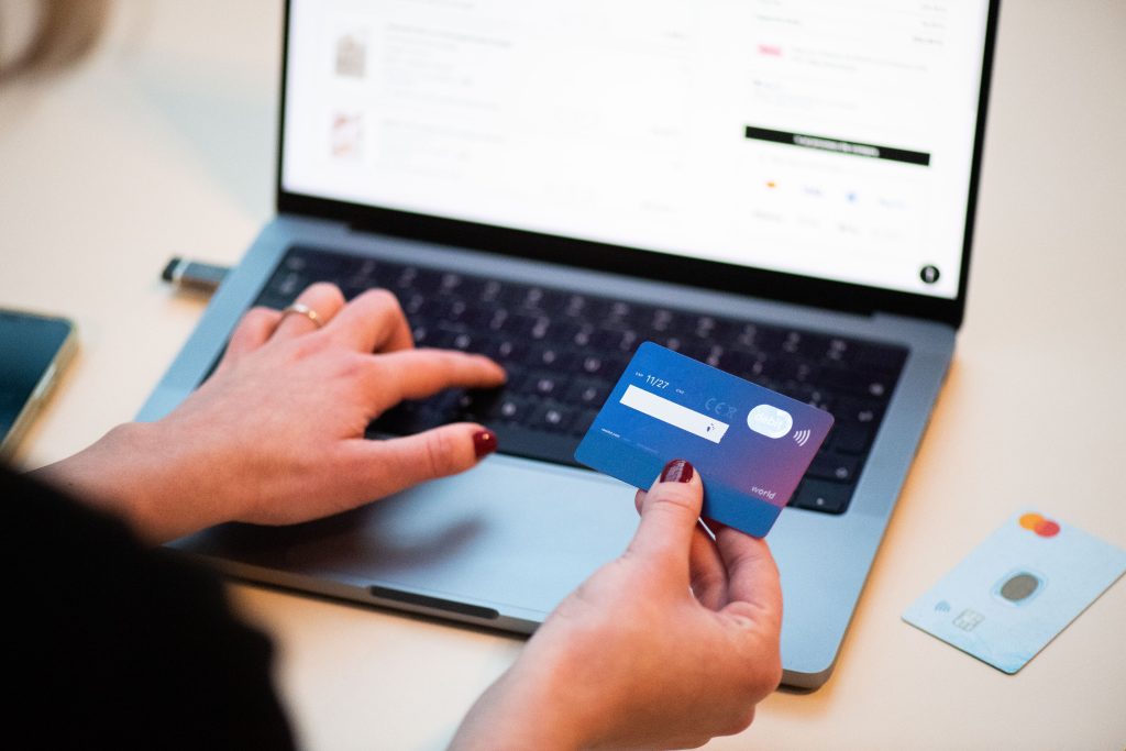 Hands holding a bank card in front of a laptop while shopping online
