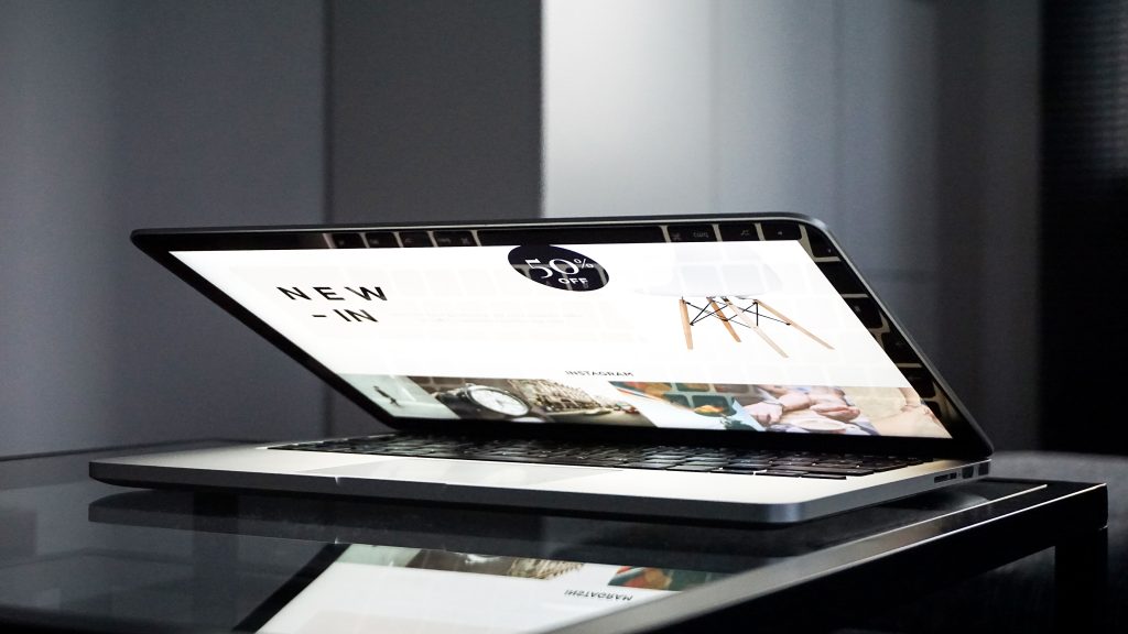 A half-open laptop on a dark desk showing a finished website on its screen