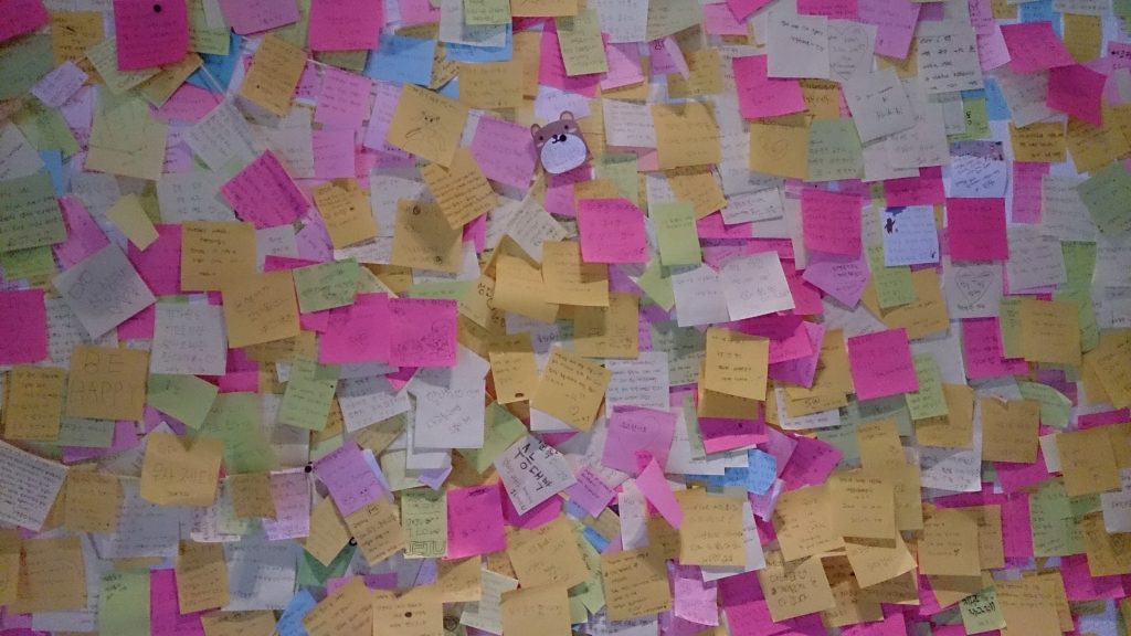 A wall covered edge to edge in coloured sticky notes